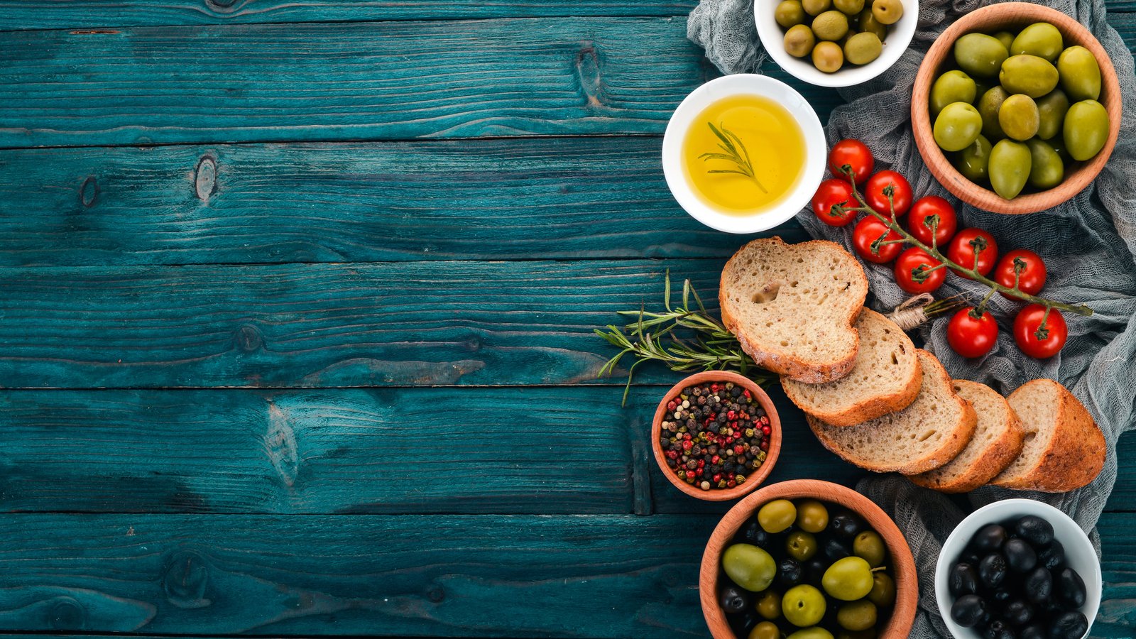 A set of green olives and black olives, and snacks. On a blue wooden table. Free space for text.