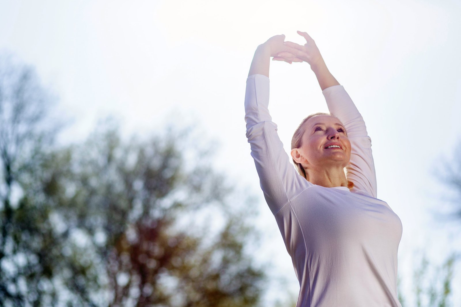 Morning gymnastics. Nice cheerful woman holding her hands up while doing morning exercises