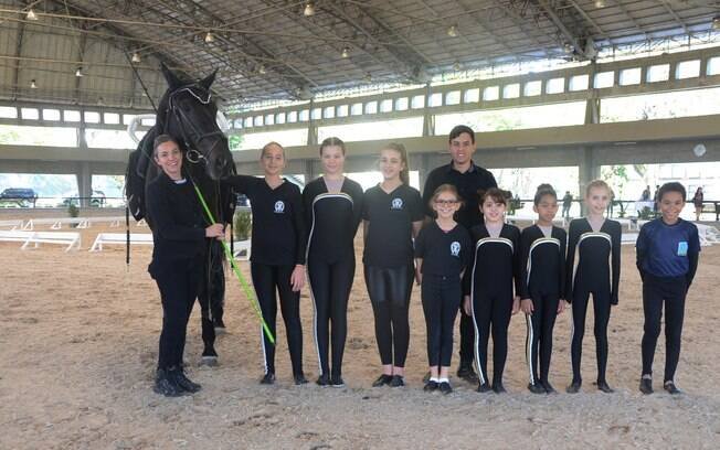 Crianças da escola de equitação da Hípica Paulista reunidas momentos de uma apresentação no picadeiro coberto do clube