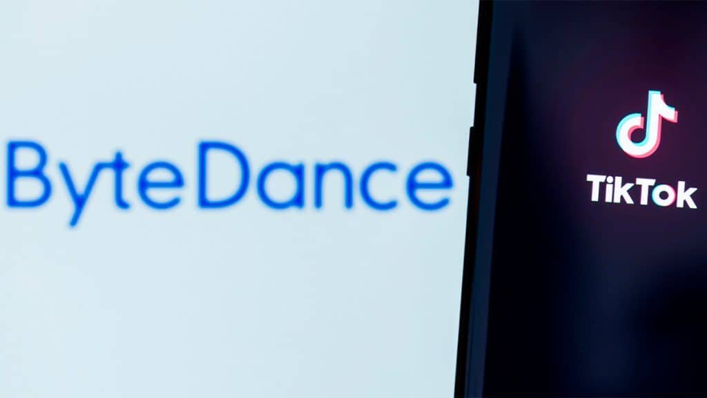 Celular com logomarca do TikTok na tela colocado na frente de monitor com logomarca da ByteDance